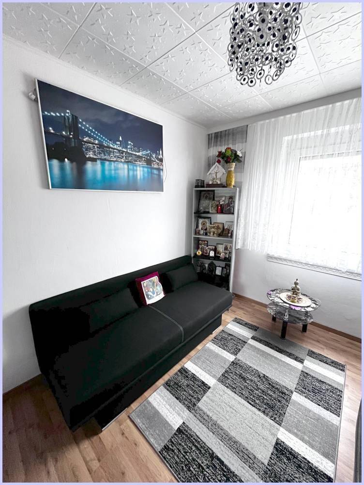 Helles Zimmer mit Schlafsofa, Bücherregal und Fenster, vielseitig nutzbar.