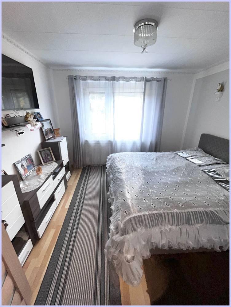 Gemütliches Schlafzimmer mit Doppelbett, Kommode und Fenster, hell und einladend.