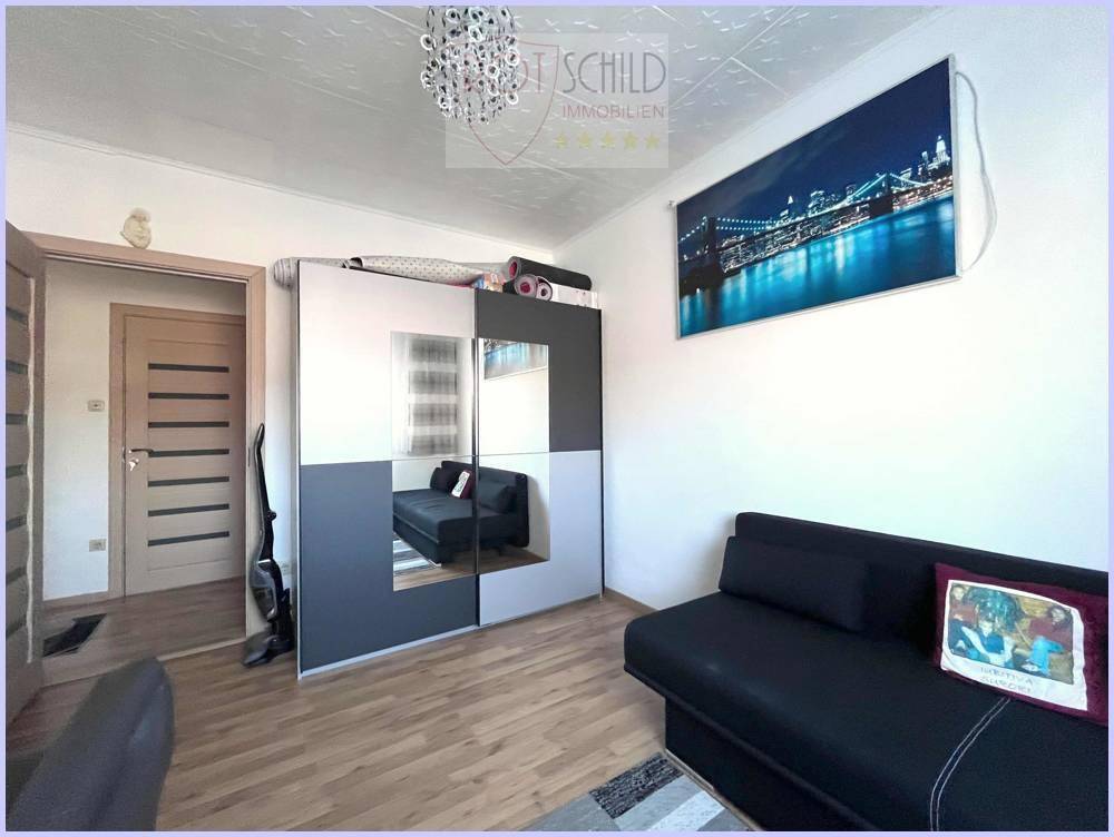Zimmer mit Schlafsofa und großem Spiegelschrank, praktisch und funktional eingerichtet.