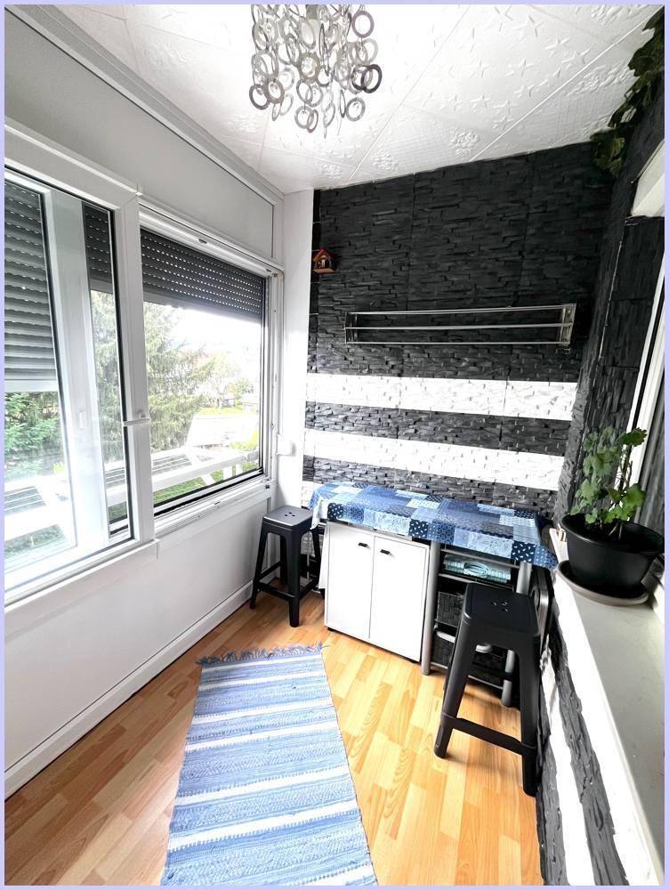 Verglaster Balkon mit Sitzgelegenheiten und dekorativer Wandgestaltung, ideal zum Entspannen.