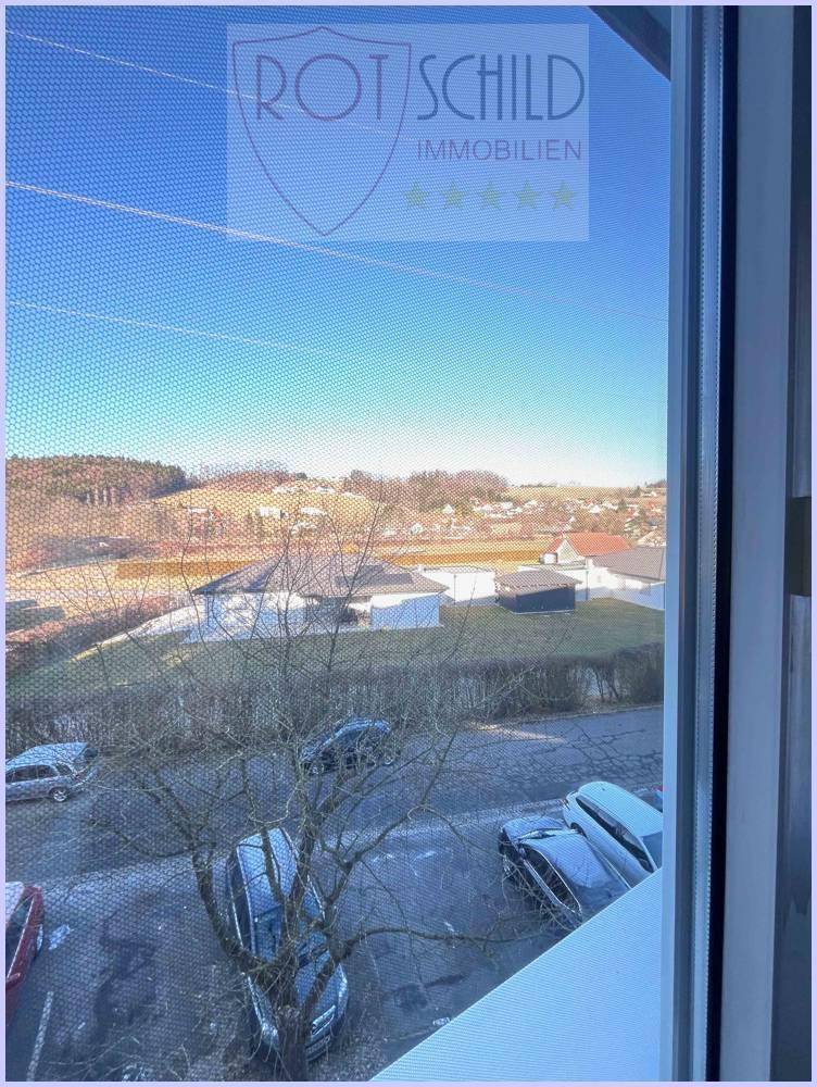 Weitblick aus dem Fenster über eine ländliche Umgebung mit Häusern und Hügeln.