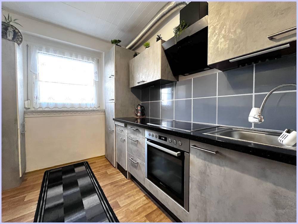 Funktionale Küche mit Fenster, Spülbecken und ausreichend Arbeitsfläche, hell und praktisch.