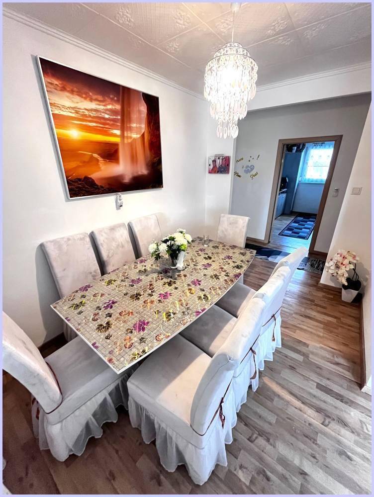 Esszimmer mit großem Esstisch, eleganten Stühlen und einem funkelnden Kronleuchter.