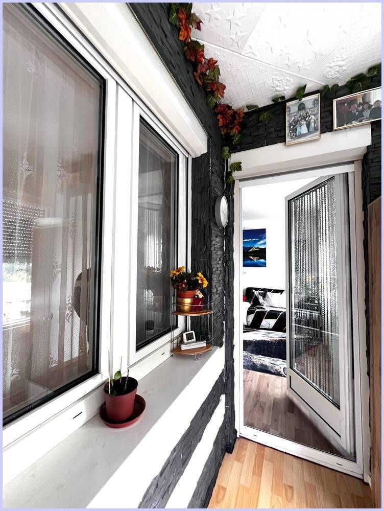 Blick vom verglasten Balkon in den Innenraum, mit Zugangstür und Fenster.