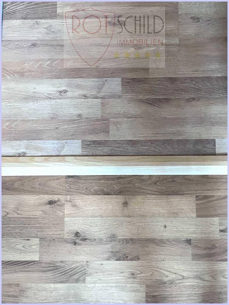 Detailaufnahme von hellem Laminatboden mit Holzmaserung, sauber und gepflegt.