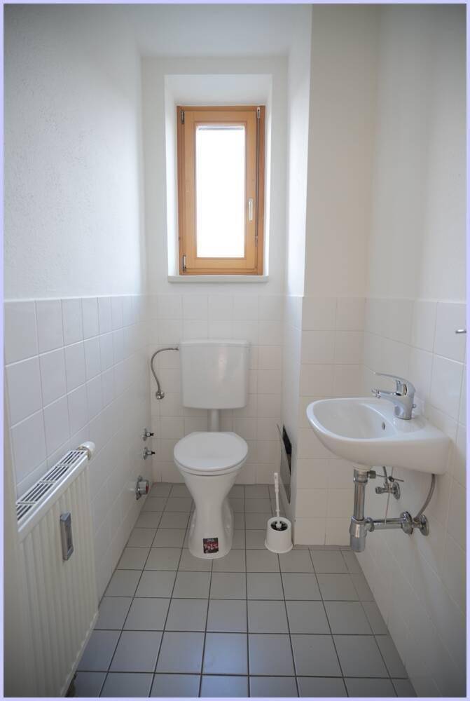 Separate Gästetoilette mit Fenster, WC und kleinem Waschbecken.