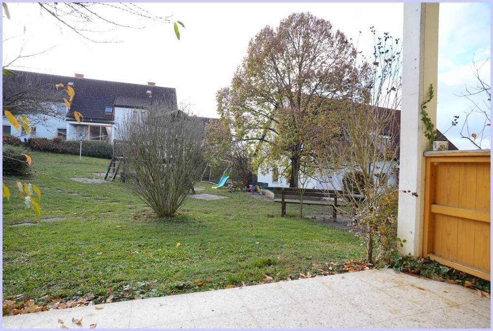 Großer, gepflegter Garten mit Rasenfläche, Bäumen und Spielgeräten im Hintergrund.