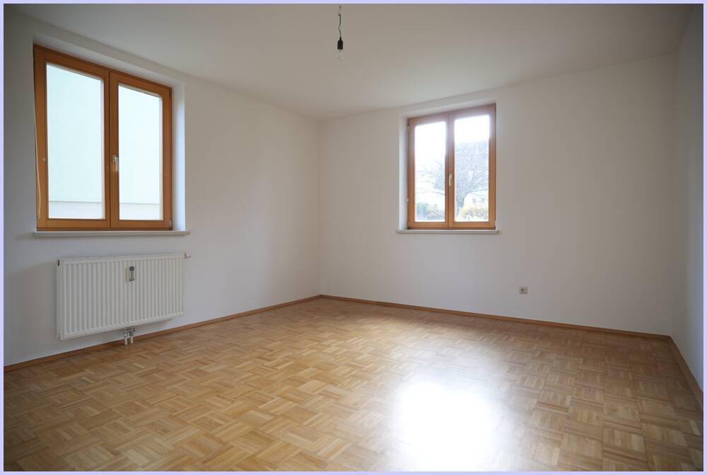 Schlafzimmer mit Parkettboden, zwei Fenstern und viel natürlichem Licht.