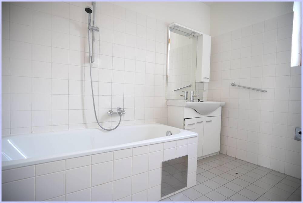 Badezimmer mit Badewanne, Duschfunktion, Waschbecken und weißen Fliesen.