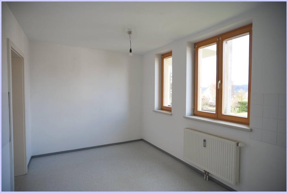 Heller Küchenraum mit Vinylboden und Fenstern, bietet viel Potenzial für eine moderne Einrichtung.