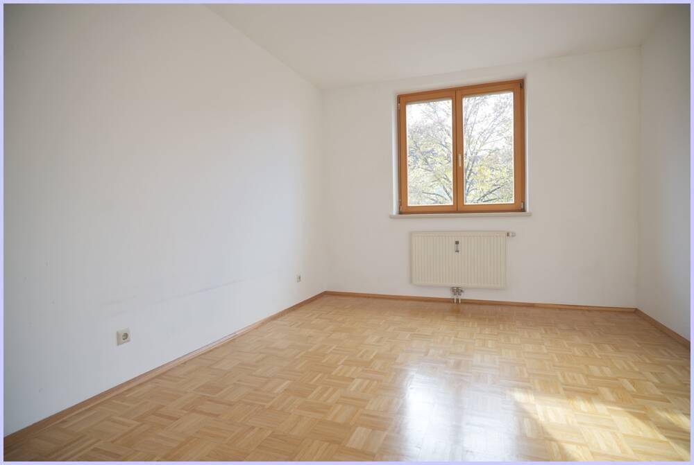 Leeres Zimmer mit Parkettboden, Fenster und Heizkörper, ideal als Schlaf- oder Arbeitszimmer.