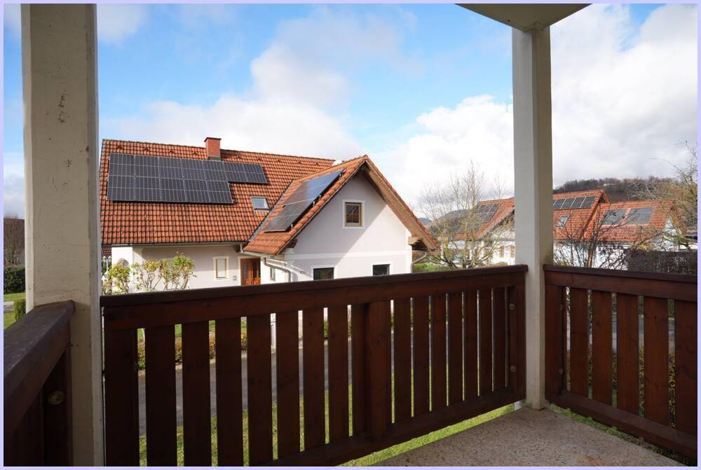 Balkon mit Holzbalken und Blick auf benachbarte Häuser mit Solaranlagen.