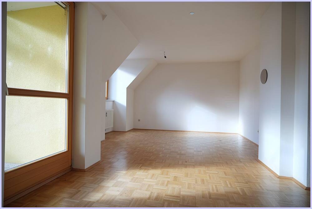 Geräumiges Zimmer mit Parkettboden, Dachschrägen und viel Tageslicht durch große Fenster.