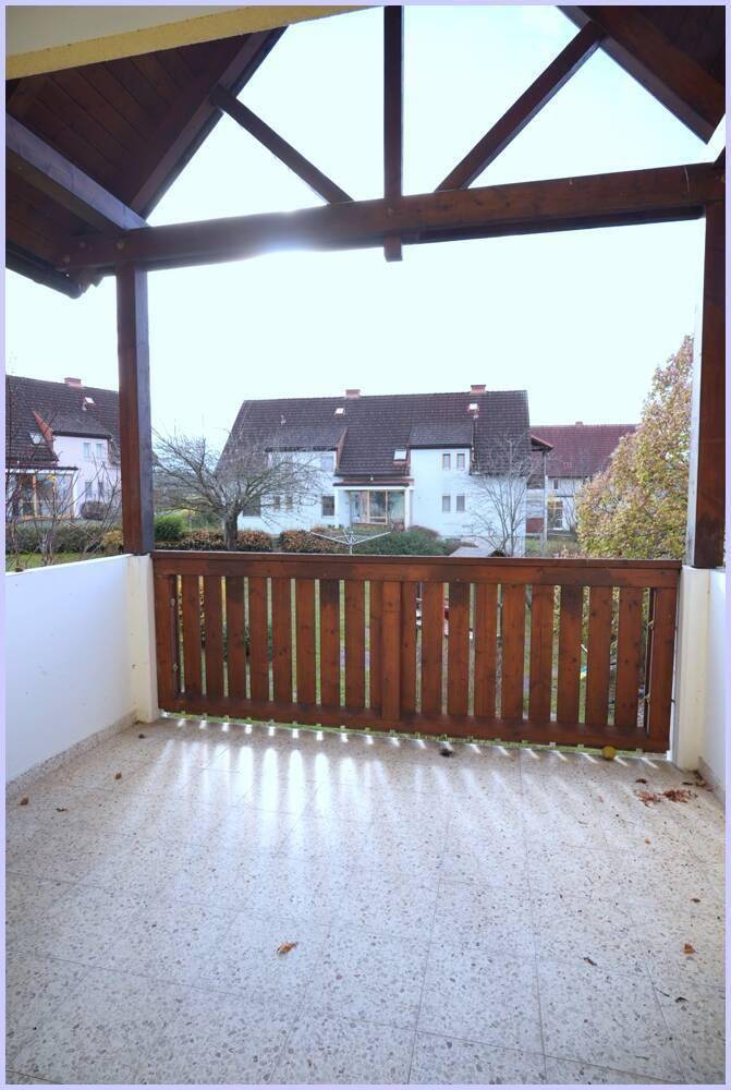 Überdachter Balkon mit Fliesenboden und Blick auf die umliegenden Häuser und Gärten.