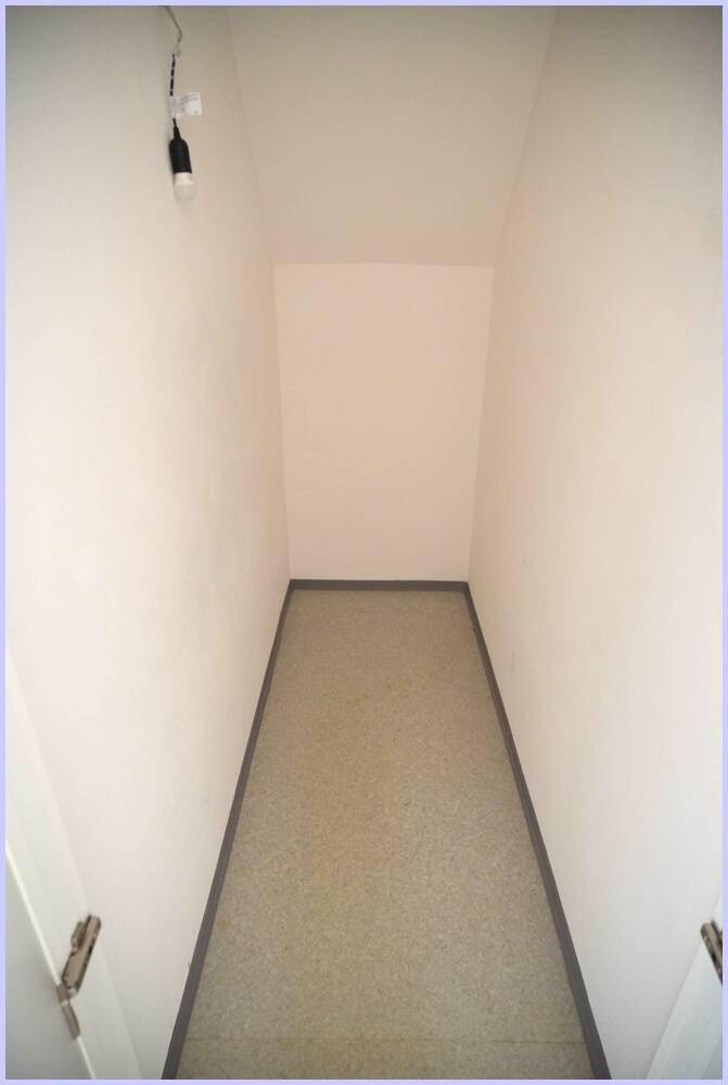 Langer, schmaler Abstellraum mit hellem Boden und weißen Wänden, ohne Fenster.