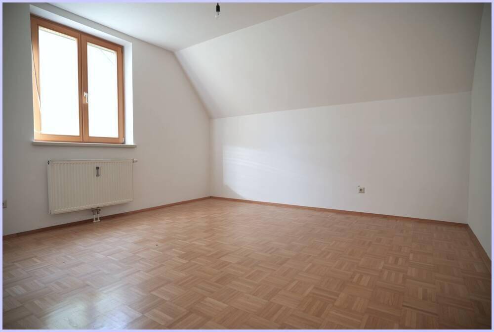 Helles Zimmer mit Parkettboden, Dachschräge und Fenster, ideal als Schlafzimmer.