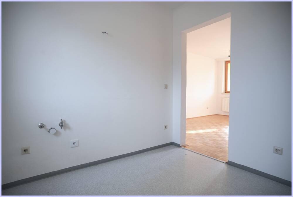 Heller Raum mit Anschlüssen und Zugang zu einem weiteren Zimmer, ideal für Waschmaschine.