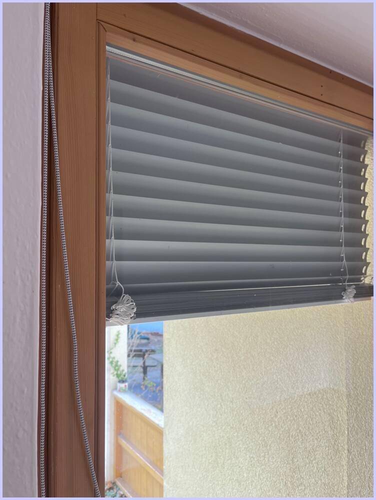 Nahaufnahme eines Fensters mit modernen Plissees, die für Sichtschutz sorgen.