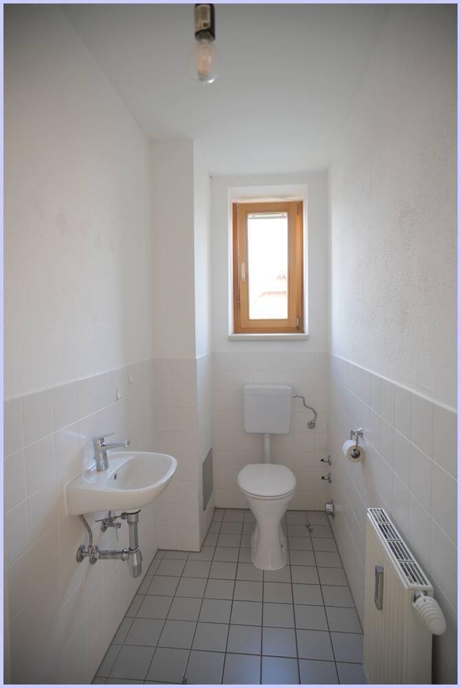 Separates WC mit Fenster, Waschbecken und Toilette, funktional und hell.