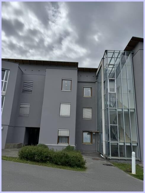 Außenansicht des Gebäudes mit zeitgenössischer Architektur und integriertem Glasaufzug.