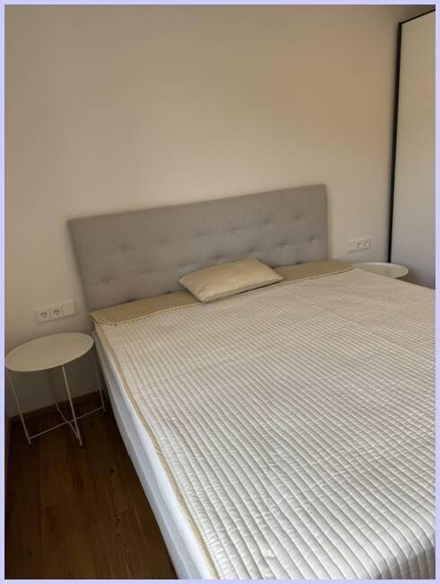 Komfortables Bett mit gepolstertem Kopfteil und kleinen Nachttischen im Schlafzimmer.