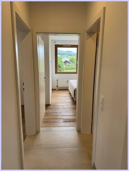 Heller Flur führt zu einem Schlafzimmer mit malerischem Blick auf die umliegende Landschaft.