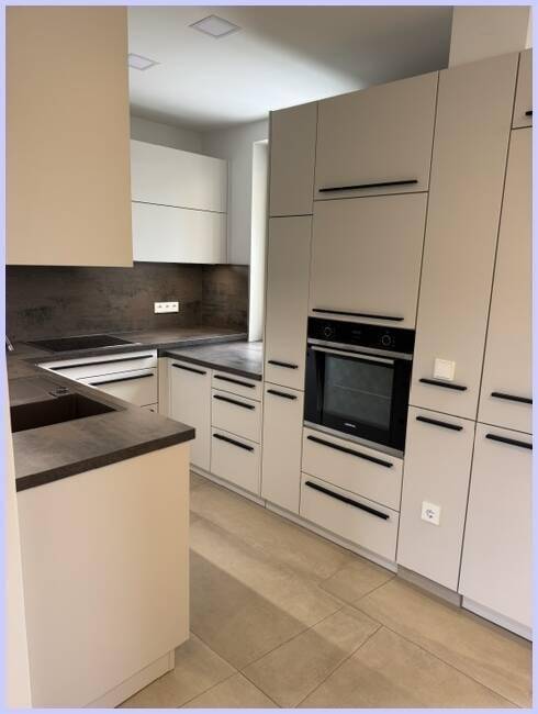Helle, moderne Einbauküche mit integriertem Backofen und viel Stauraum in den Schränken.