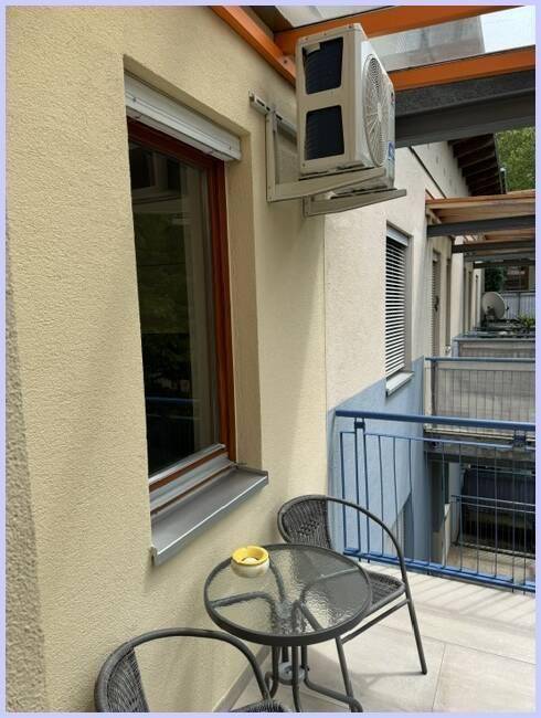 Balkon mit Sitzgelegenheiten, Klimaanlage und Fenster mit Rollläden, ideal zum Entspannen.