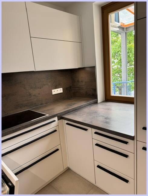 Küchenzeile mit Fenster, Spülbecken und Blick ins Grüne, ideal für helles Kochen.