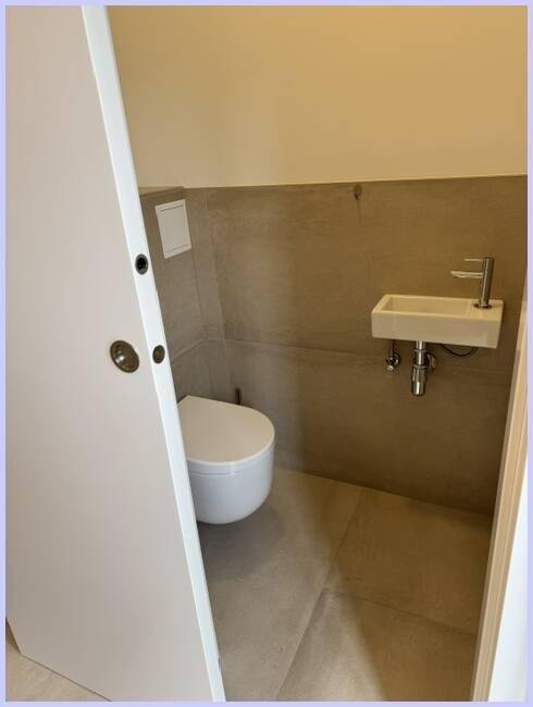 Modernes Gäste-WC mit wandhängender Toilette und kleinem Handwaschbecken.