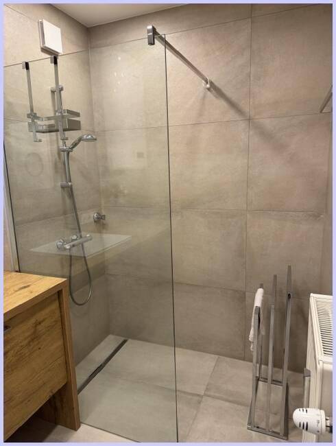 Geräumige begehbare Dusche mit Glaswand und Heizkörper im modernen Badezimmer.