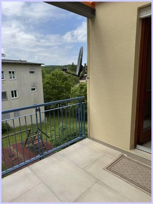 Balkon mit Blick auf die Umgebung, ein Spielplatz und ein weiteres Gebäude sind sichtbar.