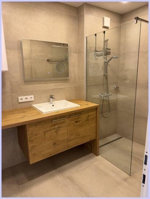 Modernes Badezimmer mit Holzwaschtisch, Einzelwaschbecken und begehbarer Dusche.