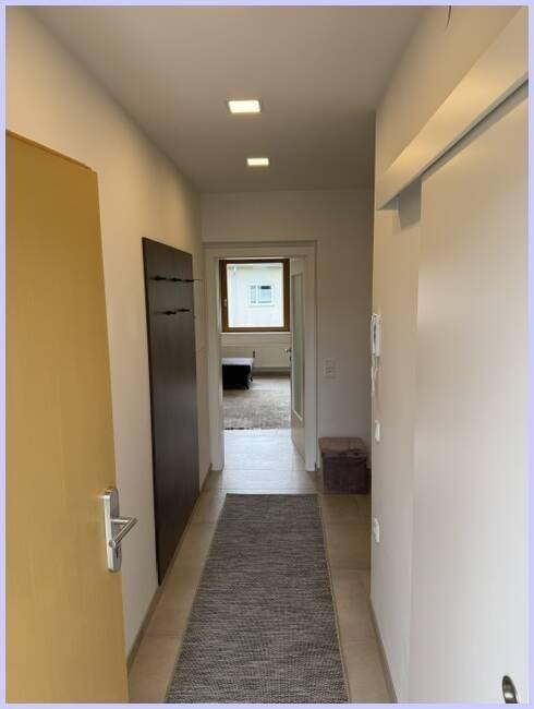 Eingangsbereich mit Garderobe und Blick in einen weiteren Raum, hell und einladend.