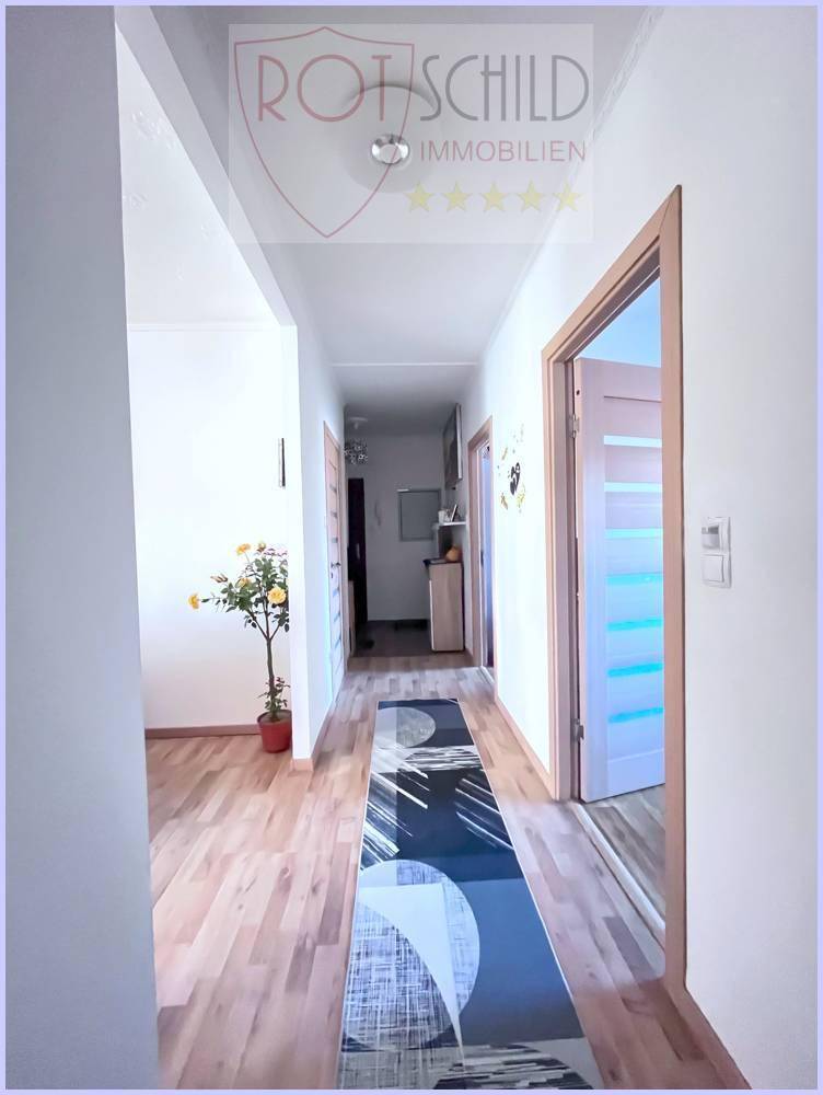 Heller Flur mit Laminatboden, mehreren Türen und einem dekorativen Läufer.