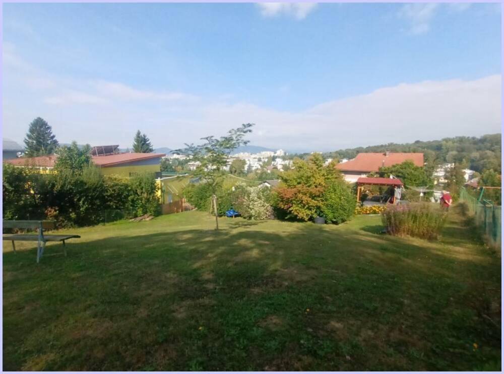 Weitläufiger Gartenbereich mit Rasenfläche, Bäumen und einem weiten Blick über die Landschaft.