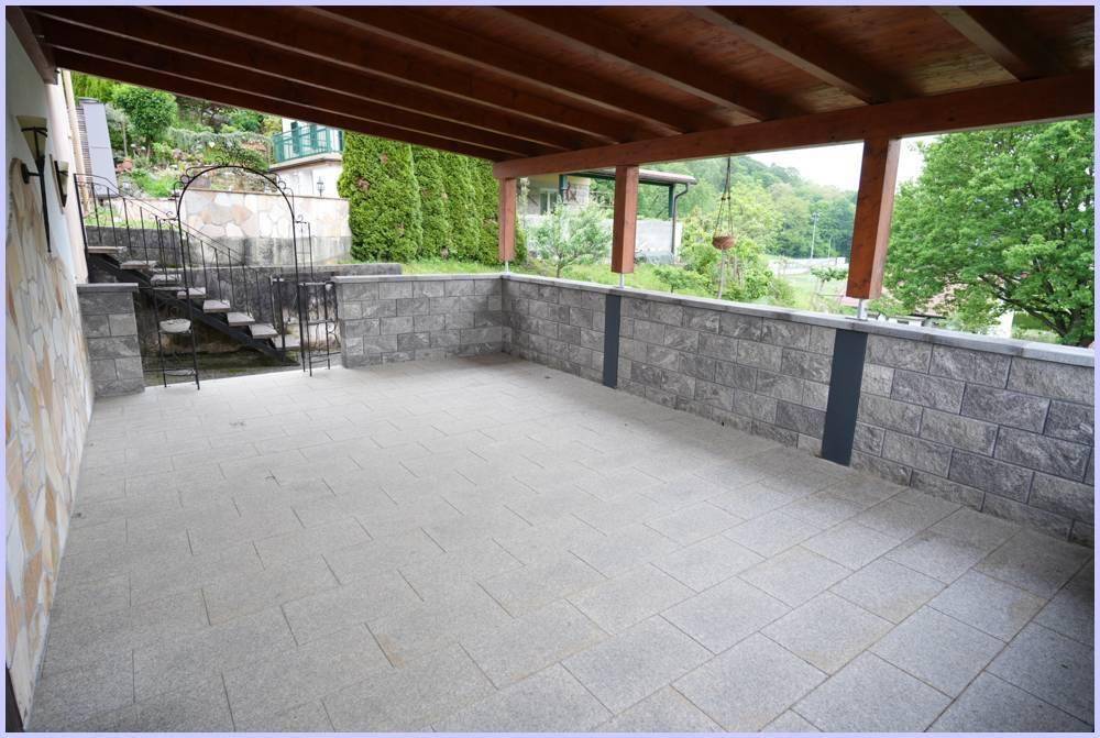 Große überdachte Terrasse mit Zugang zum Garten über eine Außentreppe, umgeben von Natur.