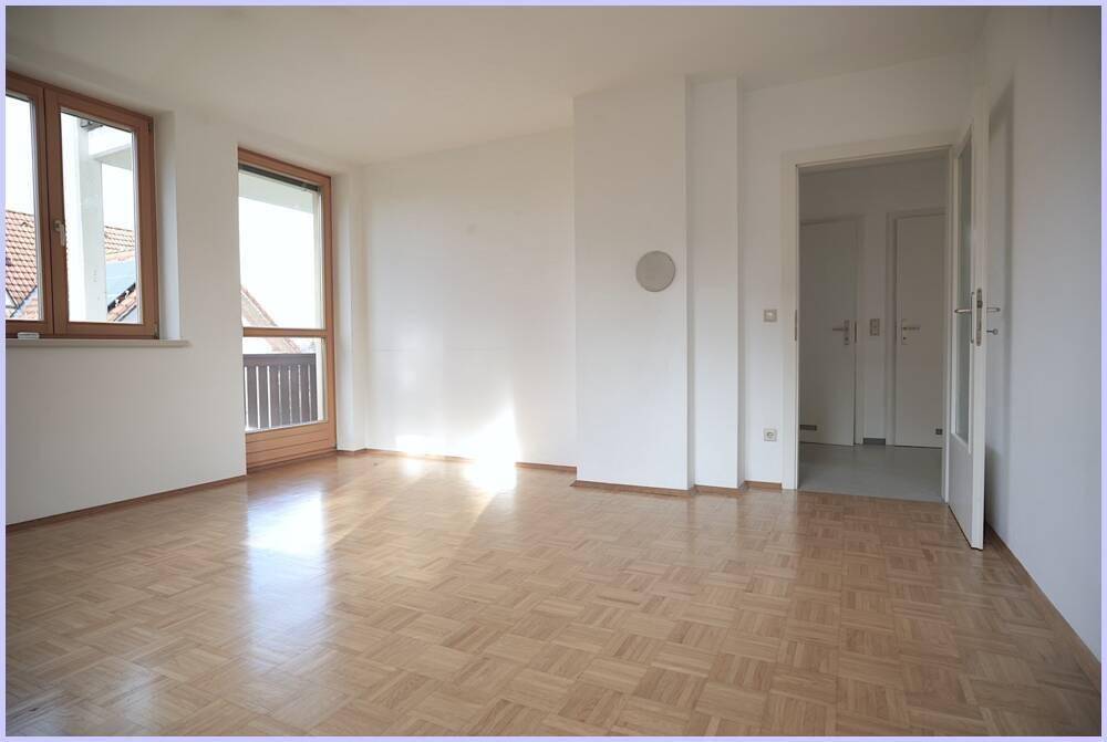Geräumiges, helles Zimmer mit Parkettboden und Blick auf den Eingangsbereich.