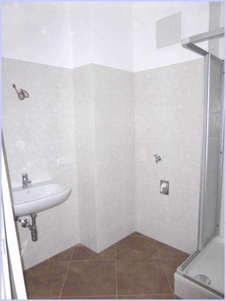 Badezimmer mit Einzelwaschbecken, hellen Fliesen und einer Duschkabine.