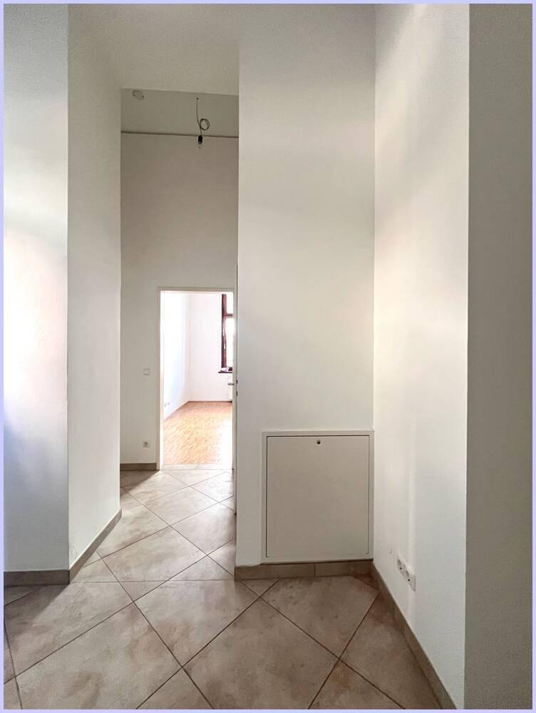 Heller Flur mit diagonal verlegten Fliesen und Zugang zu weiteren Wohnbereichen.
