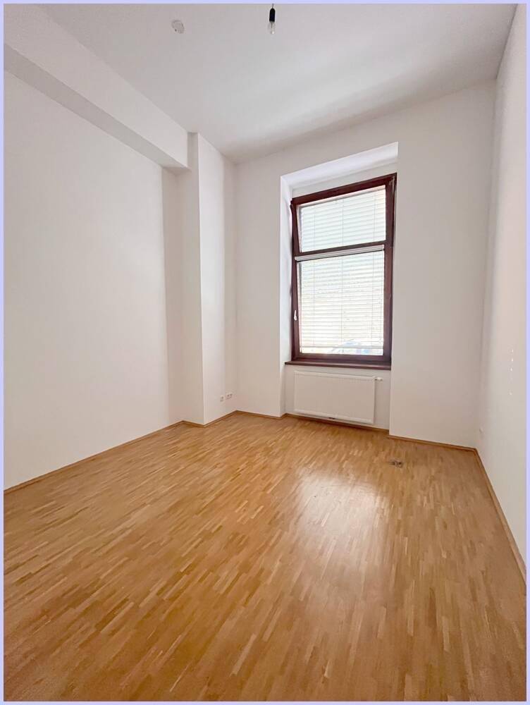 Geräumiges Zimmer mit Holzboden, weißen Wänden und einem großen Fenster für viel Licht.