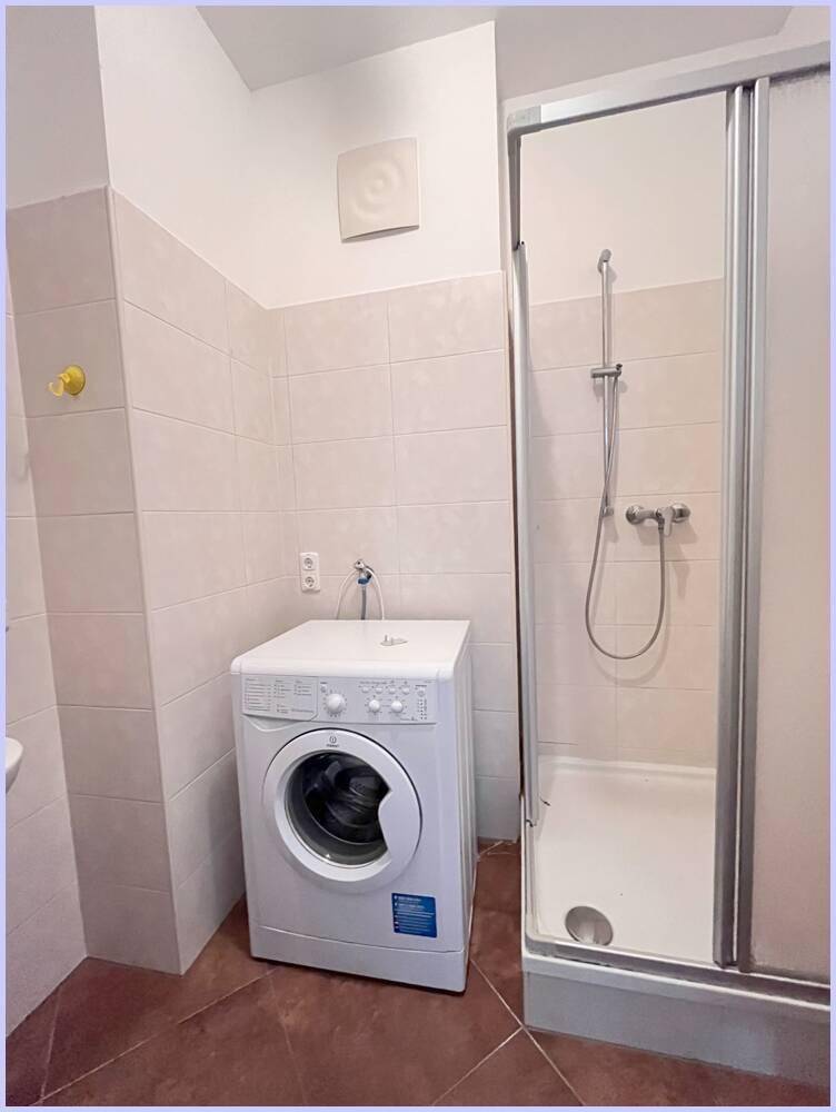 Badezimmer mit Waschmaschine, Duschkabine und Waschbecken, ideal für den täglichen Gebrauch.