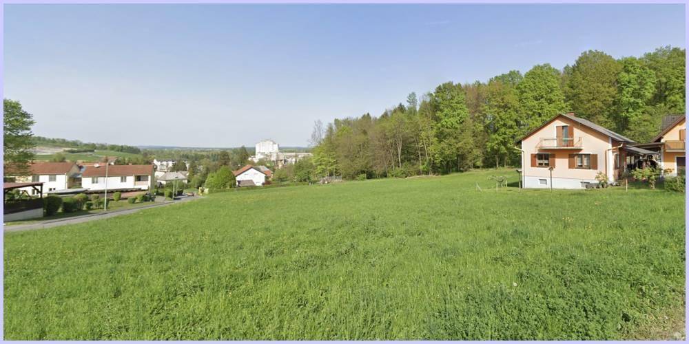 Großes, sonniges Wiesengrundstück mit Blick auf umliegende Häuser und eine Industrieanlage.