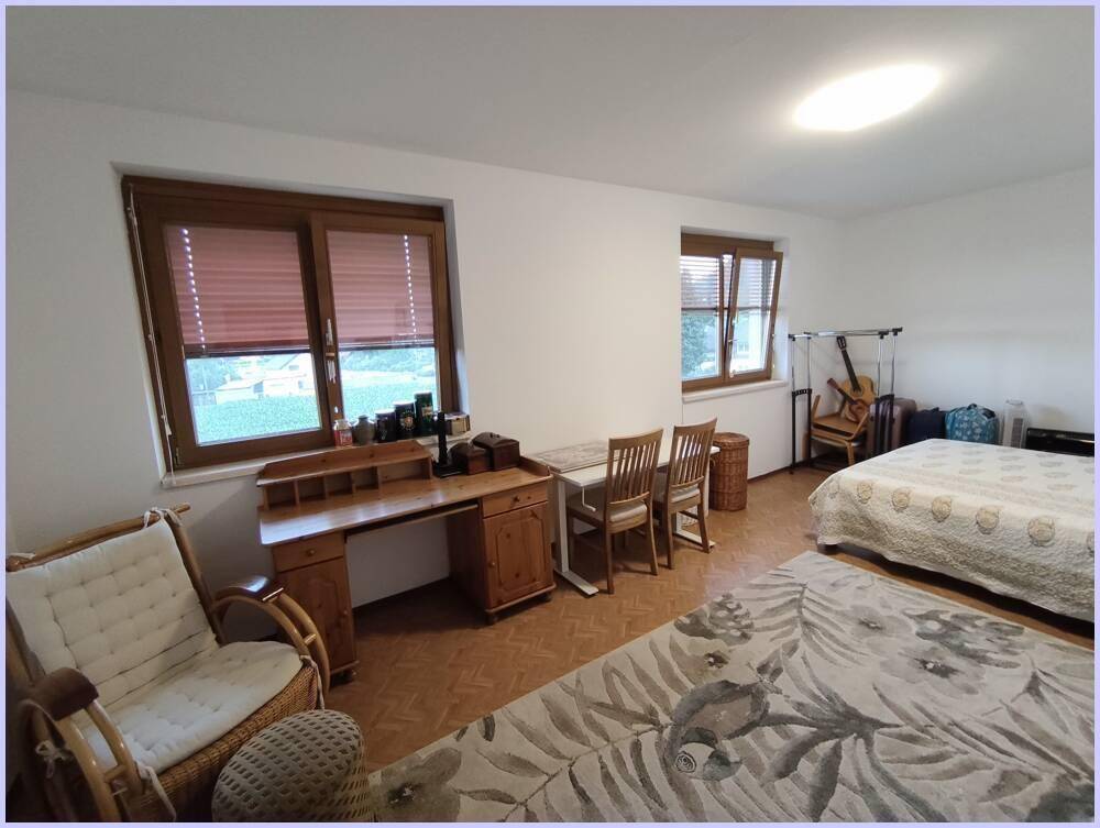 Geräumiges Schlafzimmer mit Holzmöbeln, Teppichboden und zwei Fenstern, bietet viel Tageslicht.
