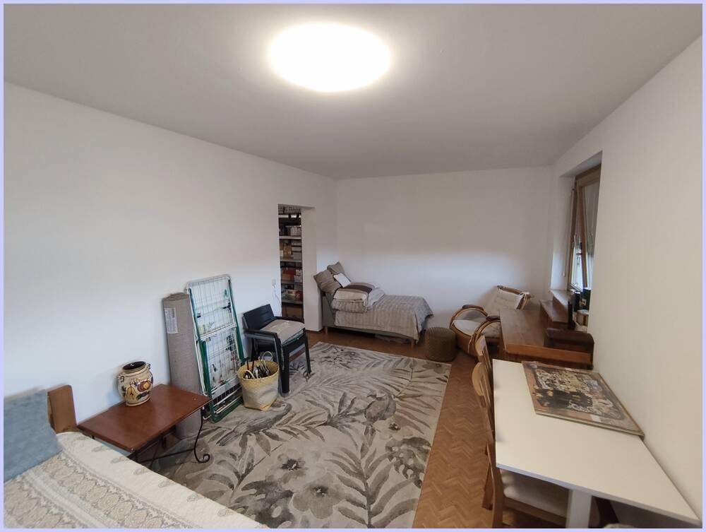 Schlafzimmer mit Bett, Schreibtisch und Teppichboden, bietet eine helle und funktionale Einrichtung.