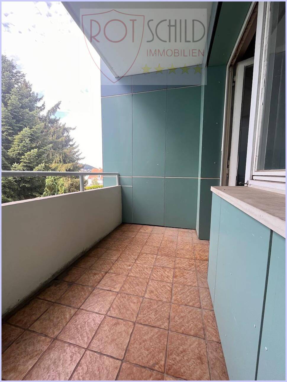 Balkon mit Fliesenboden und Blick auf Bäume, ideal für entspannte Stunden im Freien.
