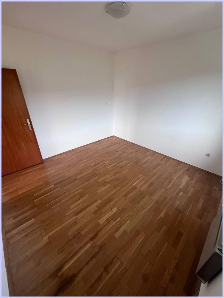 Leeres Zimmer mit Holzboden und einer Holztür, bereit zur individuellen Gestaltung.