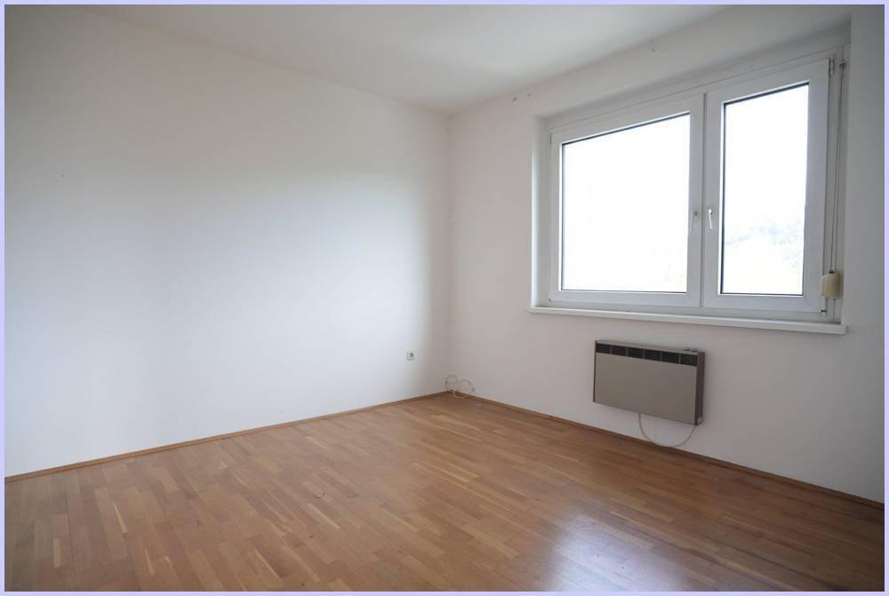 Helles Zimmer mit Holzboden und großem Fenster, das eine angenehme Atmosphäre schafft.