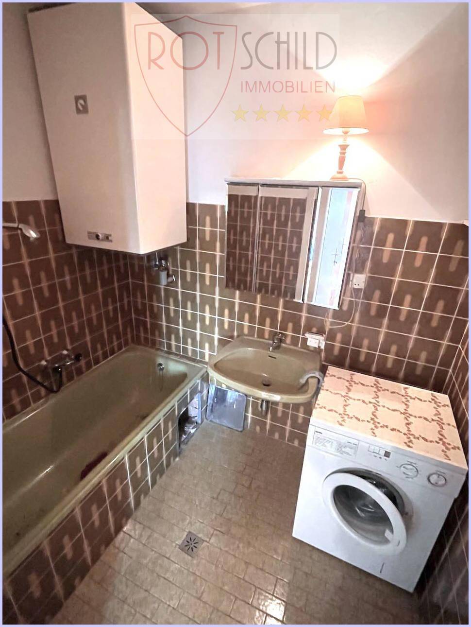 Badezimmer im 80er-Jahre-Stil mit braunen Fliesen, Badewanne, Waschbecken und Waschmaschine.