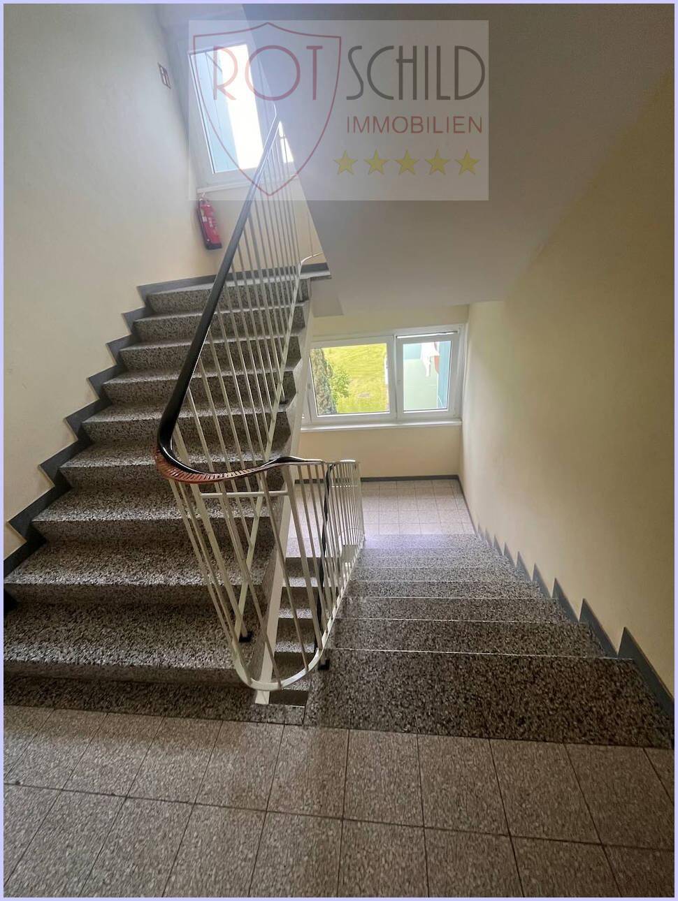 Treppenhaus mit Terrazzoboden und Geländer, das die verschiedenen Etagen verbindet.